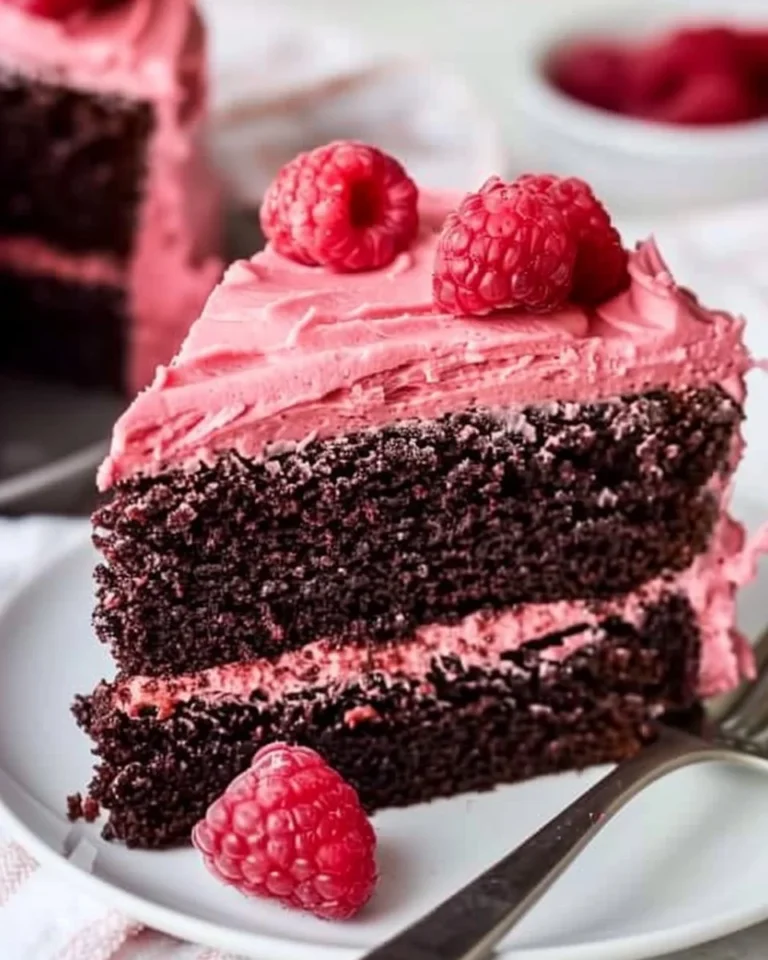 Raspberry-frosted fudgy chocolate cake beautifully presented on a plate